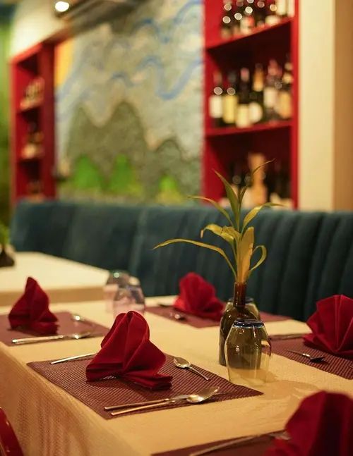 Tables laid with red napkins beside the wine shelves